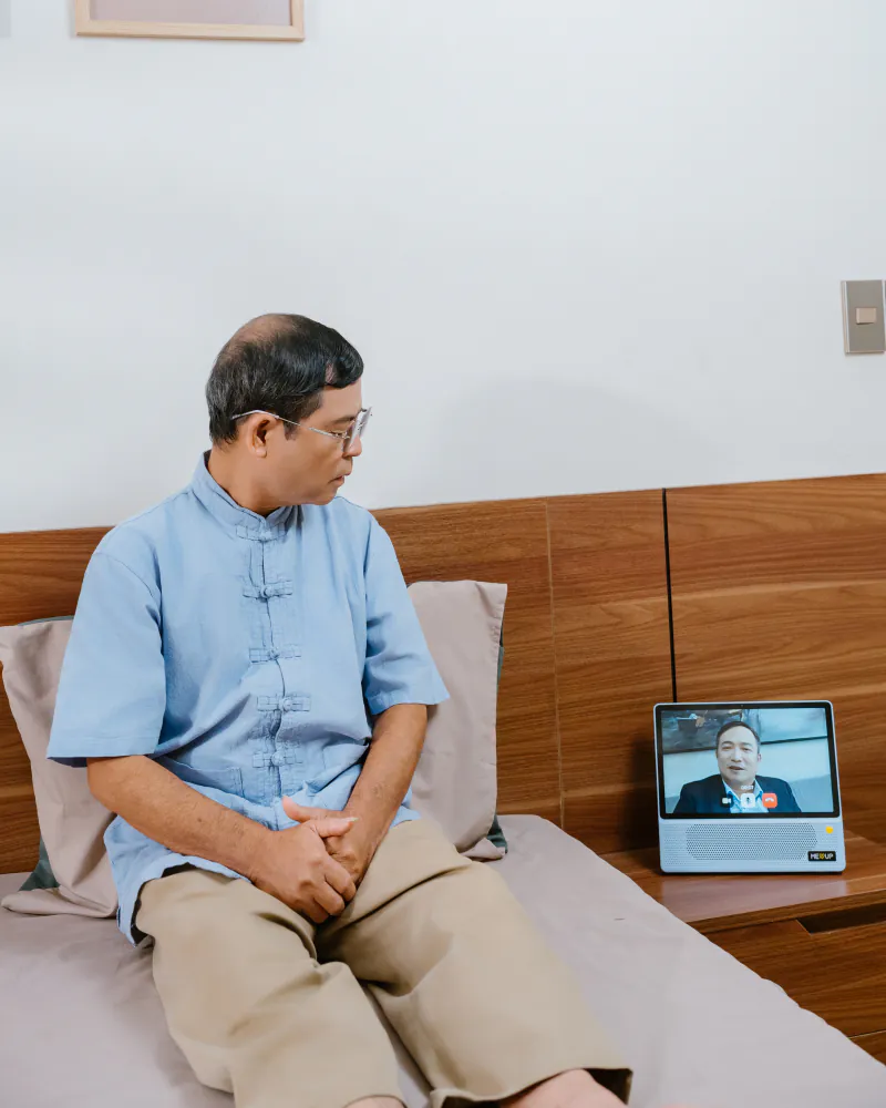 Ông ngồi trên giường, quay sang gọi video với người thân qua Meup Home H9